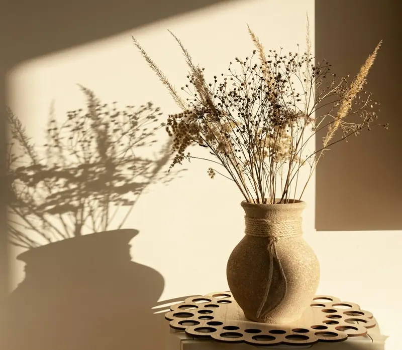 Jarrón de cerámica con ramas secas sobre una mesa